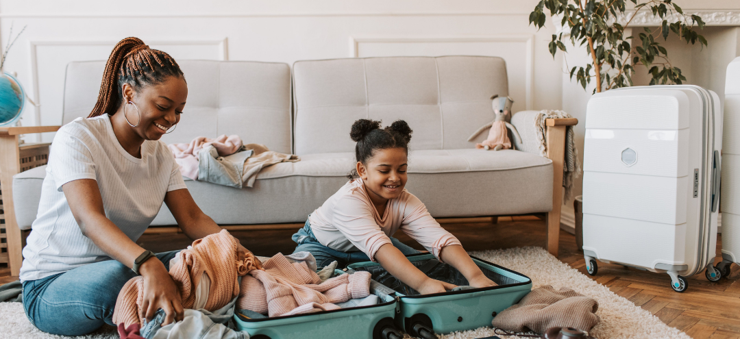 Mother and young daughter packing a suitcase together at home before a family vacation.